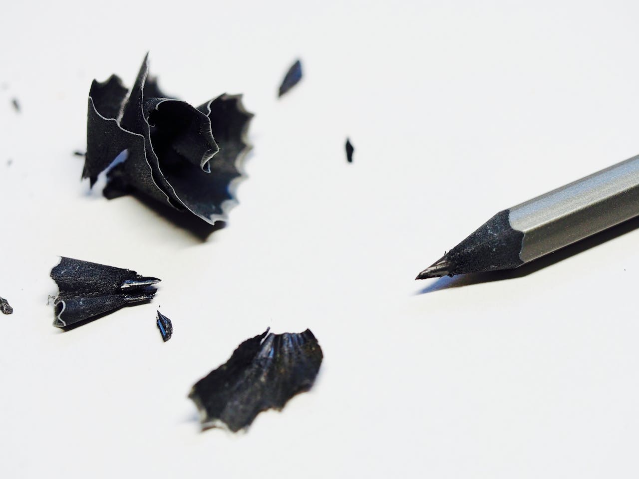 Close-up of a sharpened pencil with black shavings on a white background, ideal for creativity and office themes.